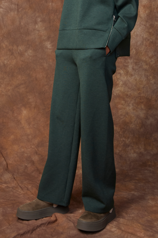Person wearing a green outfit against a brown background