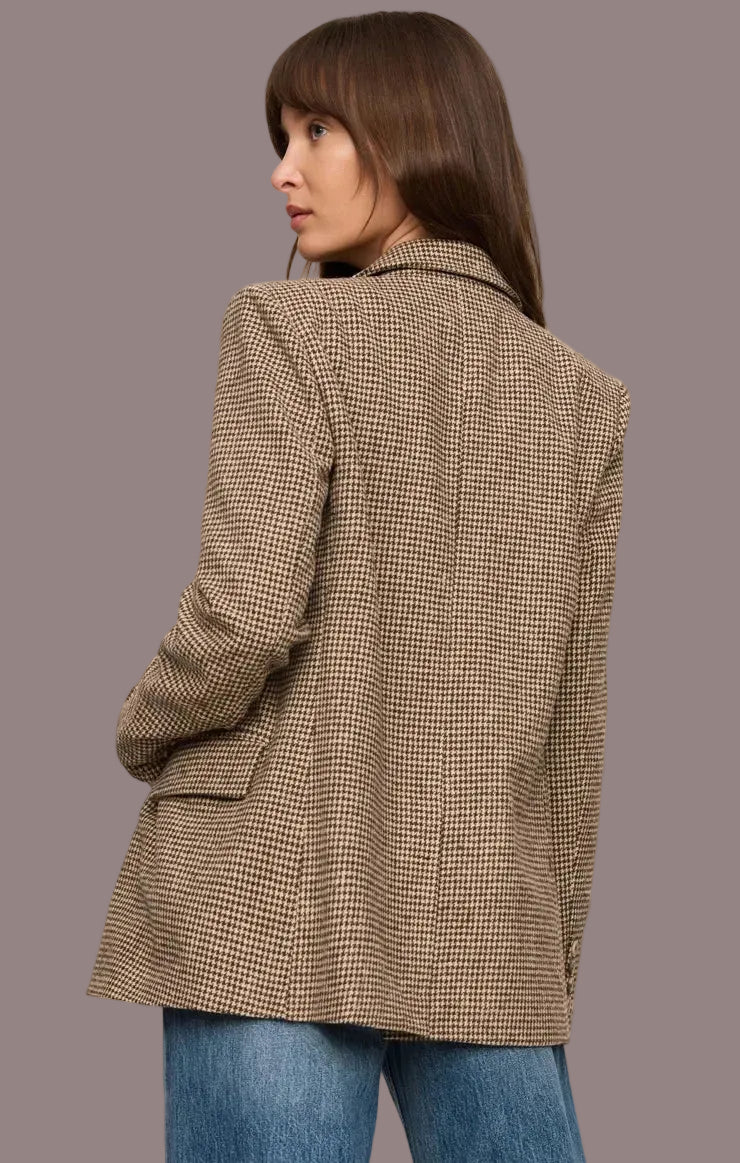 Woman wearing a brown checkered blazer and blue jeans on a beige background